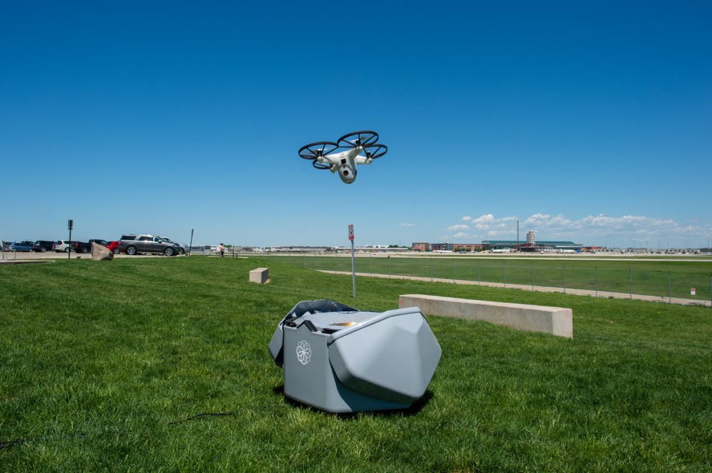 Dron autónomo despegando desde su estación base en área verde junto a instalación, sistema de seguridad autónoma con IA Chile.